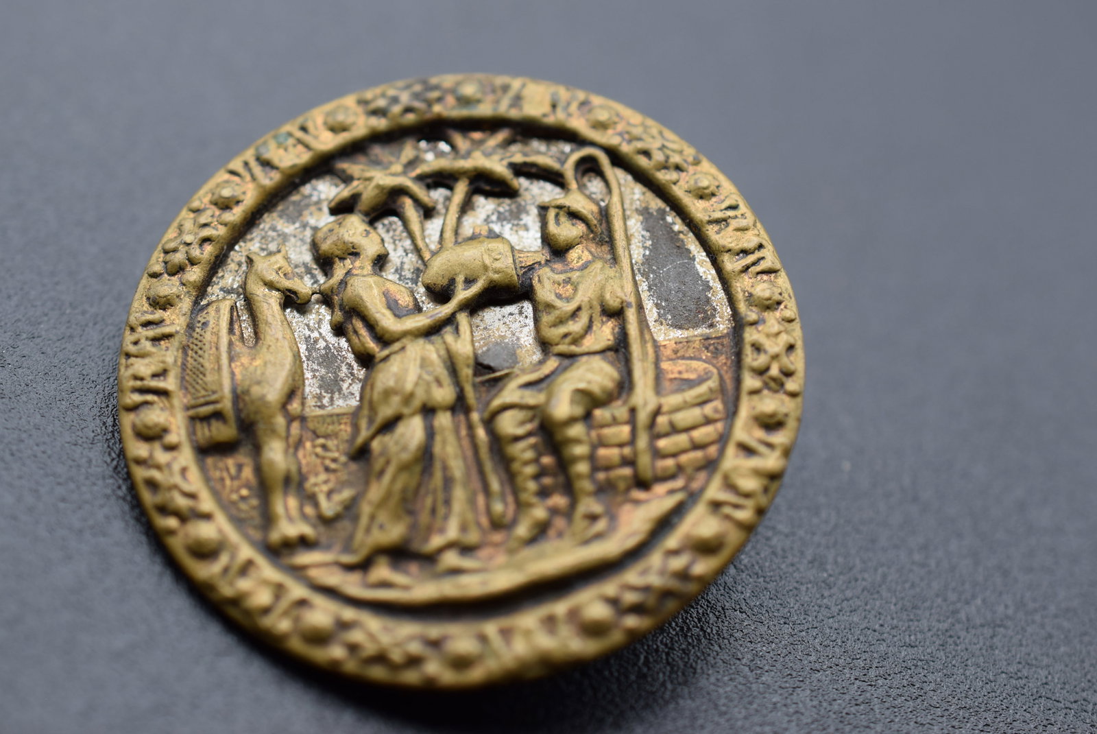 Huge vintage Brass Pictorial Repousse button 1 5/8" Lot 1196: Huge vintage Brass Repousse button measures 1 5/8" in diameter the button tells the story of a girl giving water from the well to a soldier and the camel behind her