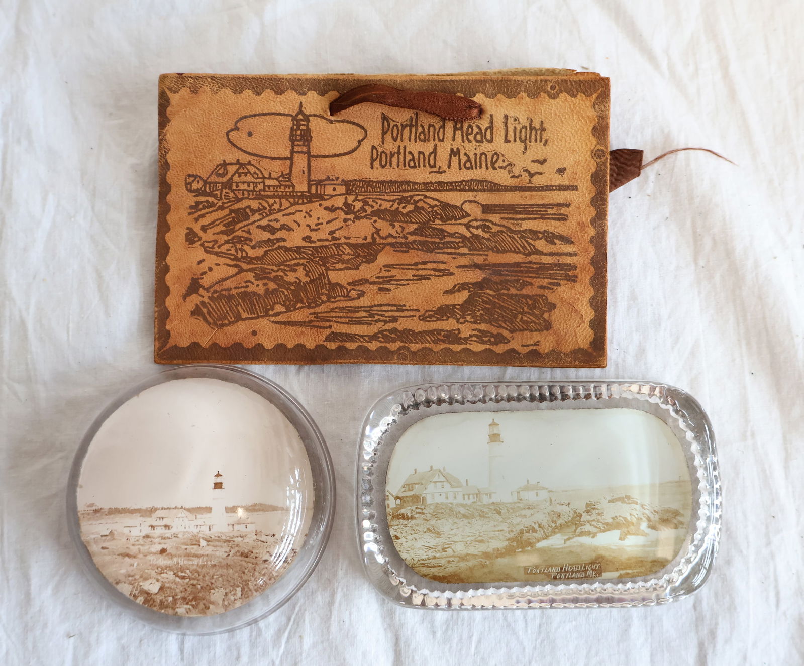 Lot of Three Portland Head Light Souvenirs- Portland, Maine: Rectangular Paperweight: 4" x 2 1/2" Round Paperweight: 3" Leather penwipe: 5 1/2" x 3 1/2" Gurley Auction Company provides In House Packing and Shipping and strive to keep costs as reasonable