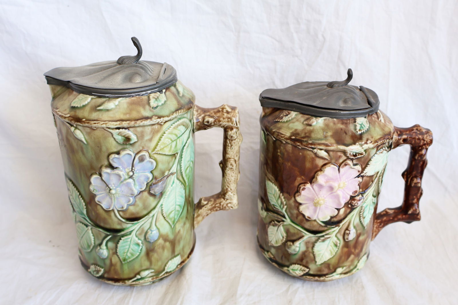 Lot of Two Majolica Pitchers with Pewter Lids: Large: 8" x 6 3/4" with handle Gurley Auction Company provides In House Packing and Shipping and strive to keep costs as reasonable as possible. Please take the time to research the cost