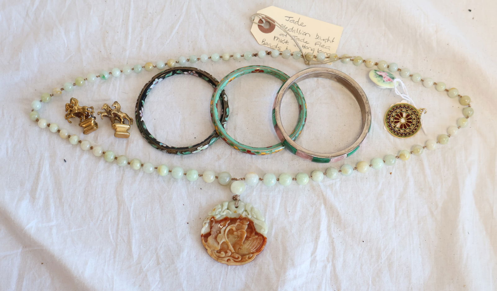 Lot of Jewelry; including Jade, Cloisonne, and Stone Inlay: Inlaid Bangle signed "950" 2 Cloisonne Bangles 1 Pendant 2 Gold tone Horse Pins Jade Beads with Carved Jade Medallion. 30" & Pendant is 2" 1 Porcelain Button Gurley Auction Company provides In
