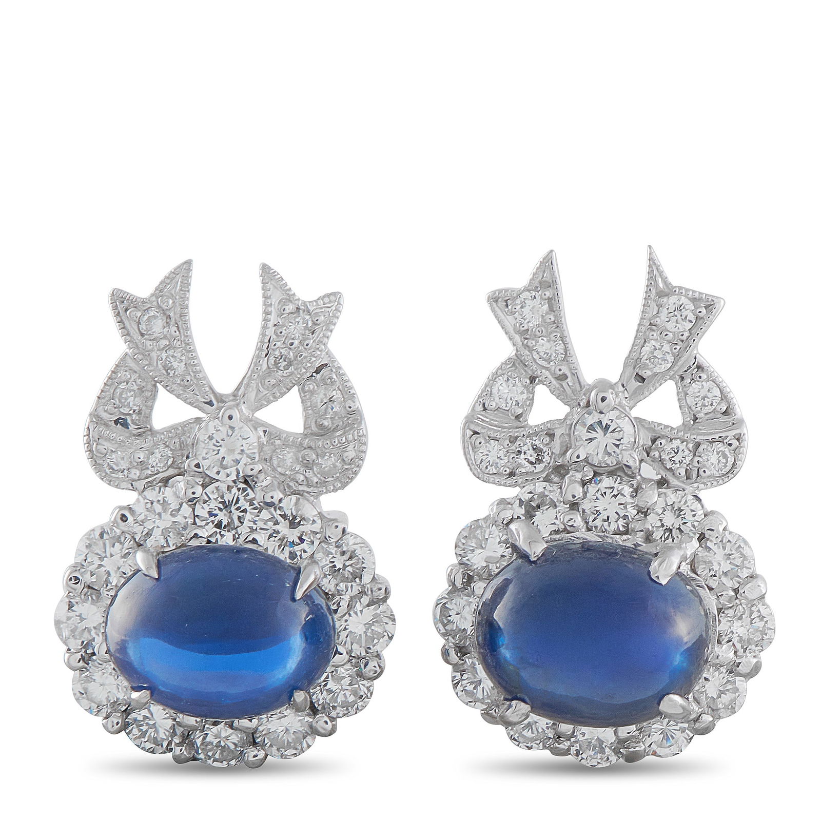 Exclusive 14K White Gold 1.84ct Diamond and Sapphire Bow Earrings: Oval cabochon sapphires set in an east–west orientation define these earrings at a glance. These blue gems are secured by four fine claw prongs that keep the profile clean and open. A halo of round