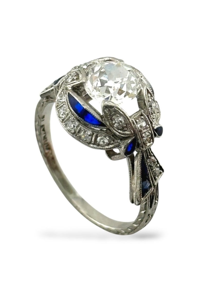 Ring Platinum, Art Deco Platinum Ring with Large 1.0 Carat Center Diamond Diamond (Natural): Platinum Ring with 1.00 Carat Diamond, Sapphires, and Accent DiamondsA striking platinum ring showcasing a dazzling 1.00 carat center diamond framed by a graceful halo of natural sapphires and complem