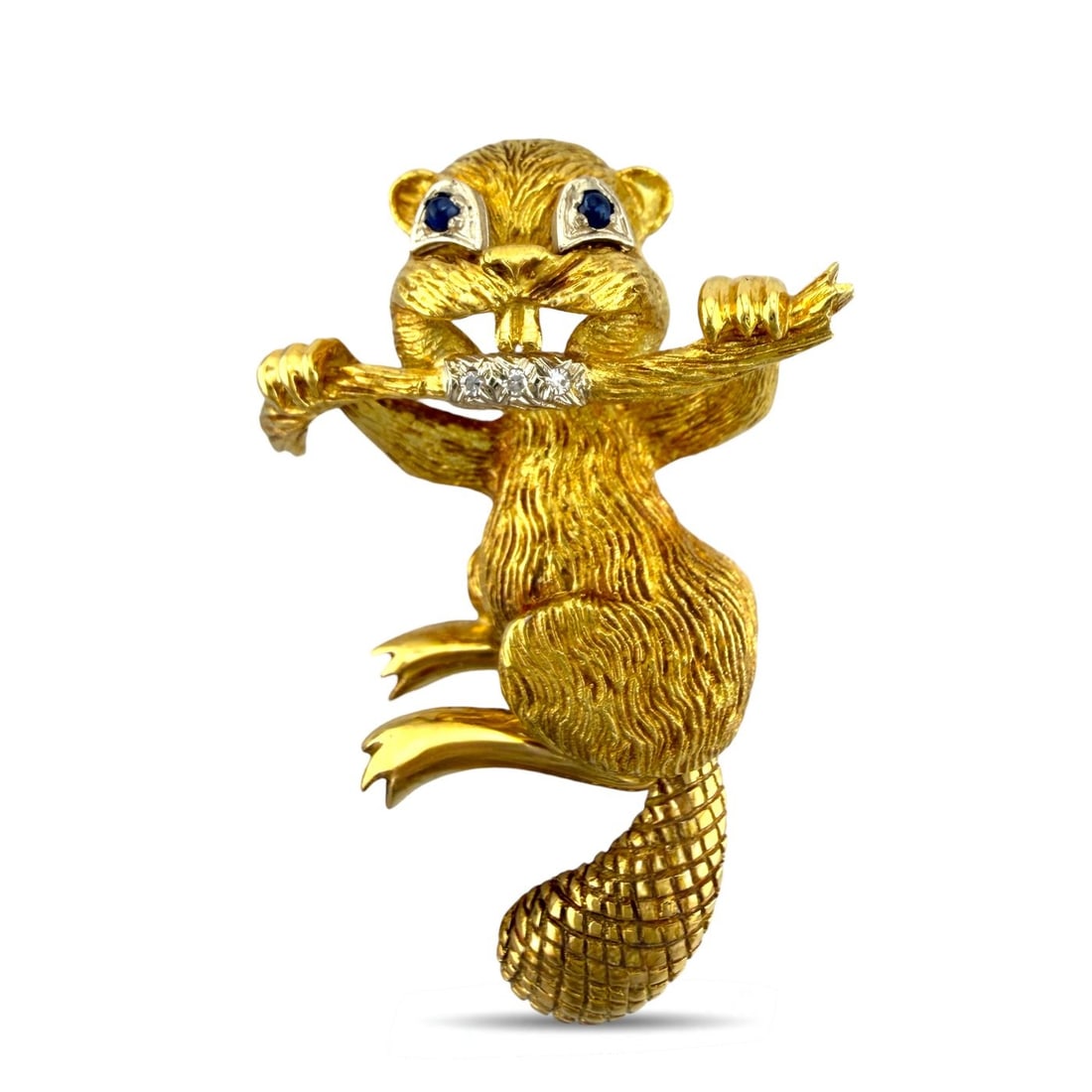 18K Yellow Gold 0.05ct Diamond and Sapphire Beaver Brooch - 0.05ct. tw. Diamond (Natural): Exclusive 18K Yellow Gold 0.05ct Diamond and Sapphire Beaver BroochA charming and finely sculpted brooch crafted in rich 18K yellow gold, depicting a detailed beaver chewing on a branch. The body