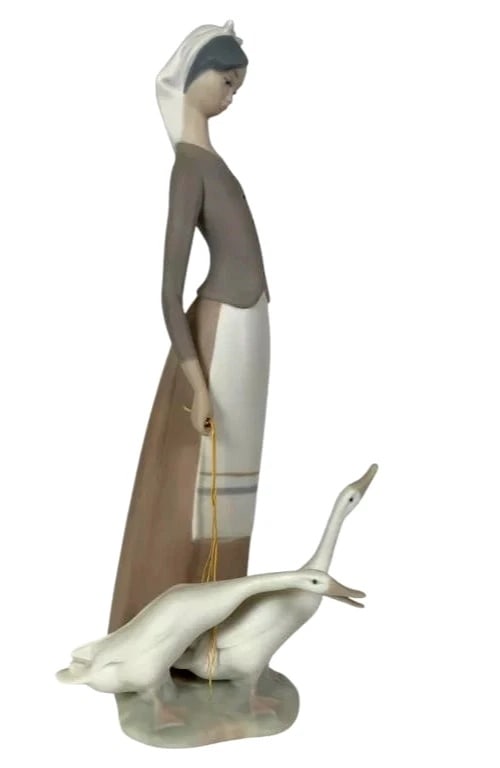 LLADRO GIRL WITH GEESE 1969-95 PORCELAIN FIGURINE 1035: LLADRO GIRL WITH GEESE 1969-95 PORCELAIN FIGURINE 1035Porcelain figurine titled Girl with Geese, model number 1035 by Lladro. Depicts a young woman standing with her hand on her hip, holding a rope ti