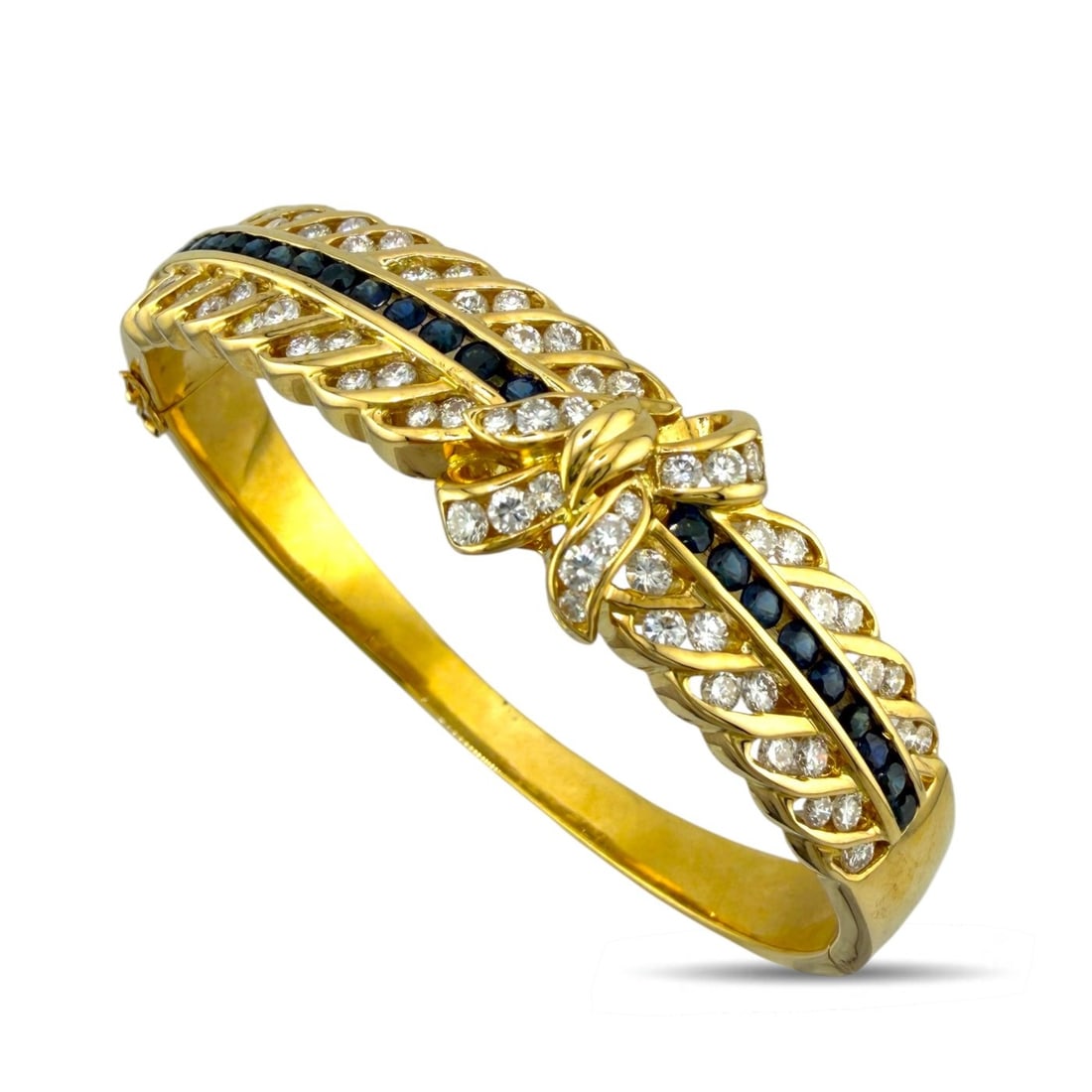 18K Yellow Gold 2.01ct Diamond and 1.00ct Sapphire Bow Bracelet: 18K Yellow Gold 2.01ct Diamond and 1.00ct Sapphire Bow Bracelet A refined yellow gold bracelet designed with two rows of diamonds and a central row of round cut sapphires, accented by a sculpted gold 