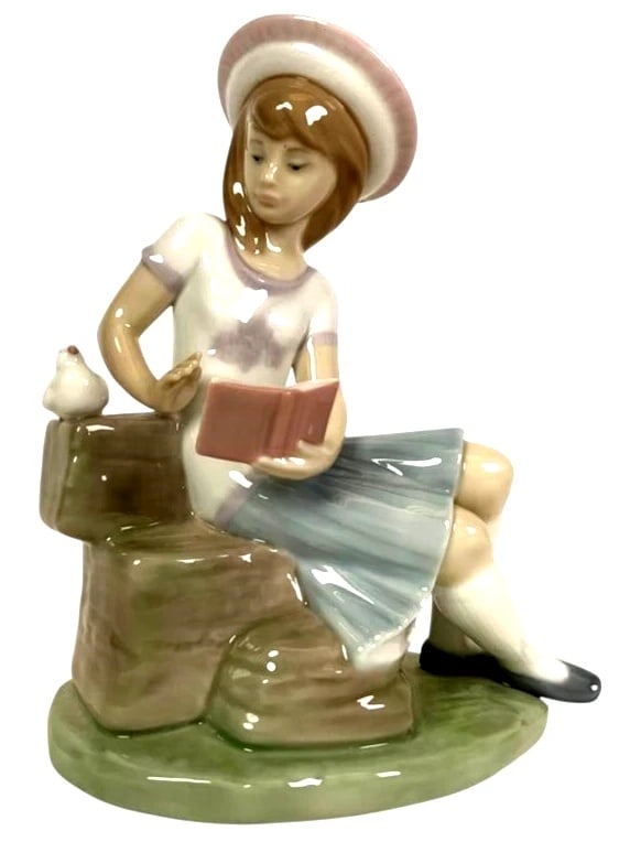 LLADRO SUNDAY'S CHILD (GIRL) LLADRO RETIRED: 1997: LLADRO SUNDAY'S CHILD (GIRL) LLADRO RETIRED: 1997Lladro porcelain figurine titled Sundays Child, model number 6024. Depicts a seated girl in a hat and dress, reading a book with a small bird perched o