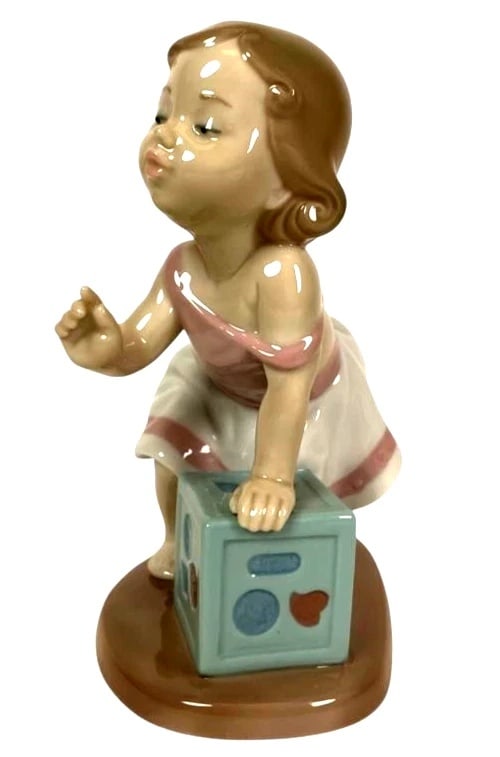 LLADRO MY FIRST STEP 1997-01 PORCELAIN FIGURINE 6428G.: LLADRO MY FIRST STEP 1997-01 PORCELAIN FIGURINE 6428G.Lladro porcelain figurine titled 'My First Step,' model number 6428, depicting a young girl taking her first steps while leaning on a block. The p