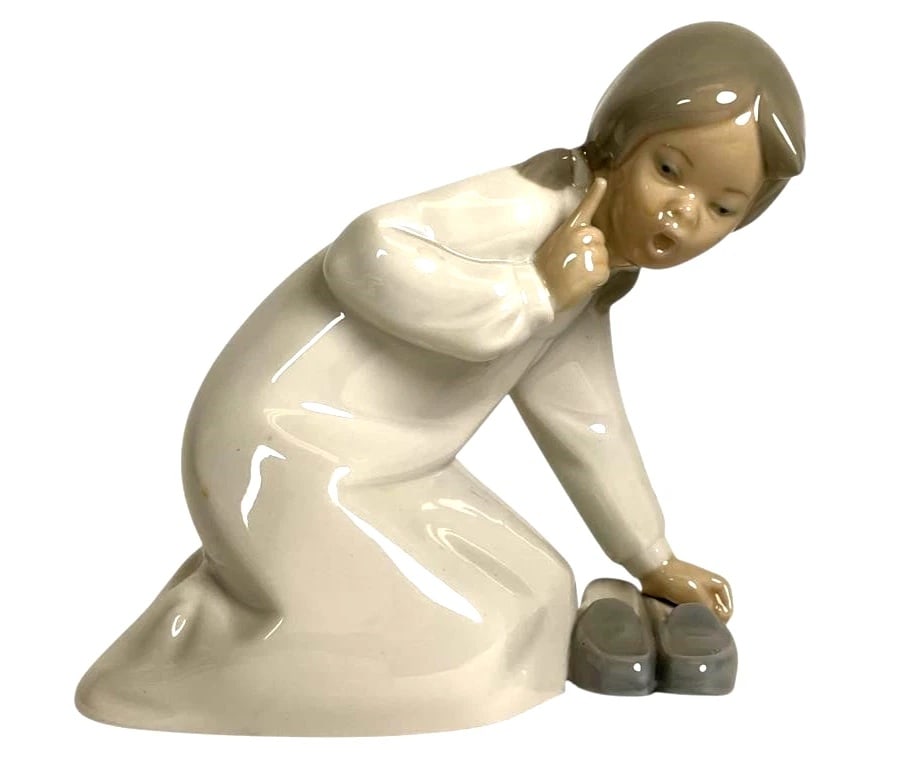 Little Girl with Slippers 1014523 Lladro Figurine: Little Girl with Slippers 1014523 Lladro FigurineLladro porcelain figurine titled 'Little Girl with Slippers,' model number 4523. Depicts a kneeling girl with pigtails, leaning towards a pair of small