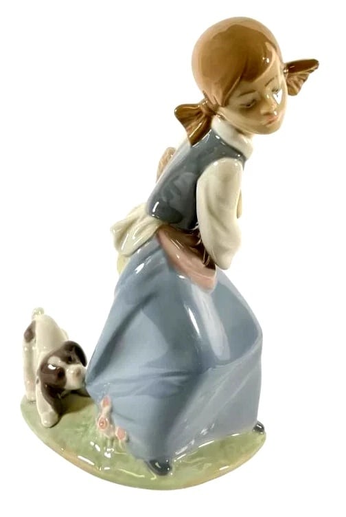 LLADRO NAUGHTY DOG 1978-95 PORCELAIN FIGURINE 4982G: LLADRO NAUGHTY DOG 1978-95 PORCELAIN FIGURINE 4982GLladro porcelain figurine titled Naughty Dog (model #4982), depicting a playful scene of a girl holding a basket and a dog with flowers. Measures 8 i