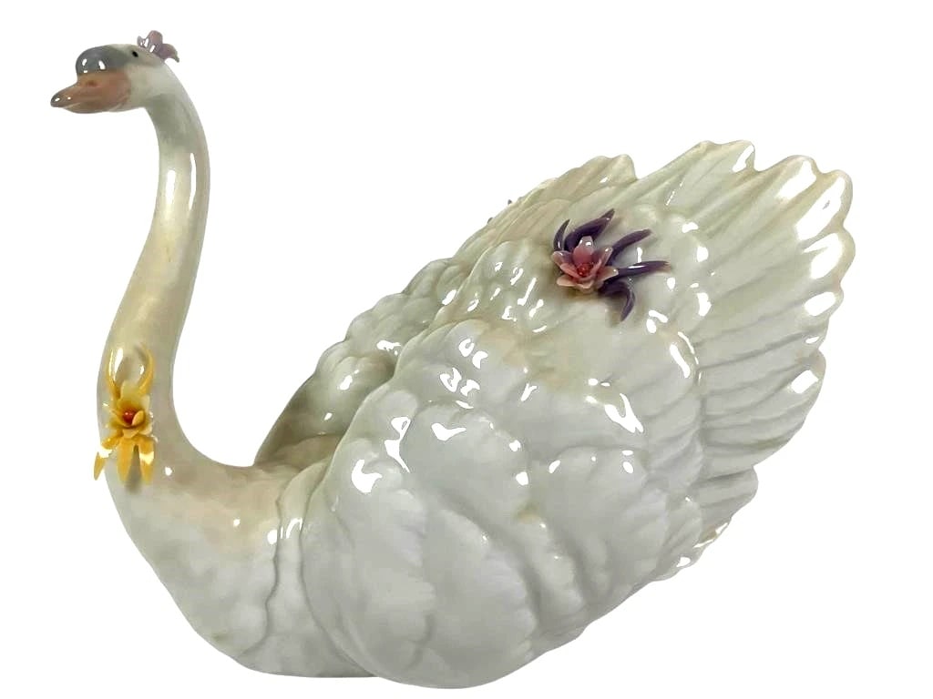 LLADRO WHITE SWAN WITH FLOWERS PORCELAIN FIGURINE 6499.: LLADRO WHITE SWAN WITH FLOWERS PORCELAIN FIGURINE 6499.Lladro 'Swan with Flowers' porcelain figurine, reference #6499. Features a white swan with pastel floral accents in purple, pink, yellow, and blu