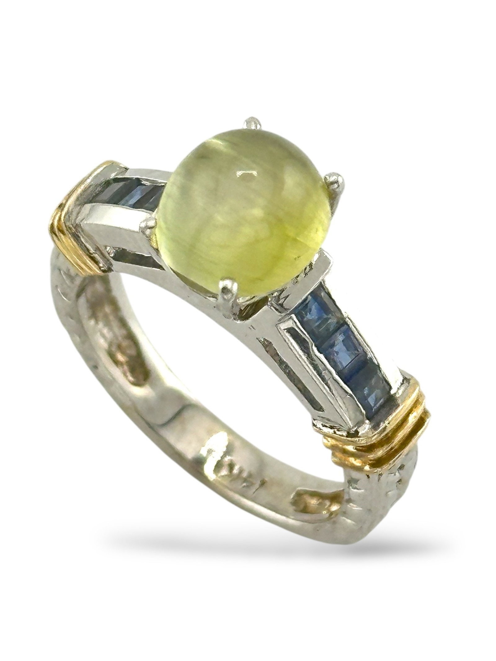 Natural Cat's Eye Chrysoberyl Diamond Gold Ring: 14K White Gold Ring with 2.2 Carat Natural Cat's Eye Chrysoberyl and Sapphires This striking women's ring showcases a rare and beautifully luminous 2.2 carat natural cat's eye chrysoberyl, known for