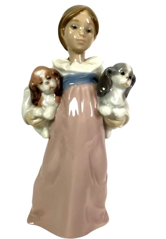 LLADRO ARMS FULL OF LOVE PORCELAIN FIGURINE 01006419: LLADRO ARMS FULL OF LOVE PORCELAIN FIGURINE 01006419Porcelain figurine titled 'Arms Full of Love,' model 6419, crafted by Lladro. Features a young girl in a pastel dress holding two puppies, measuring