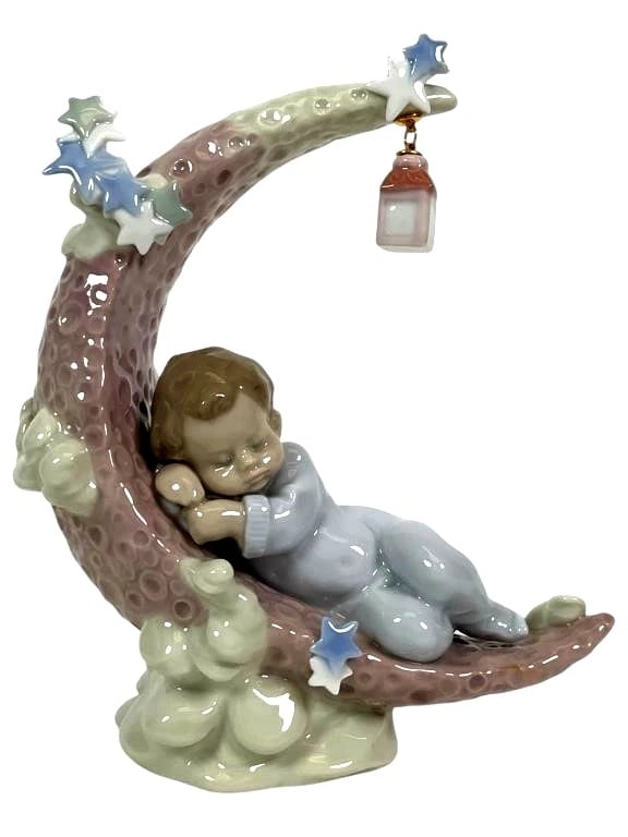 LLADRO HEAVENLY SLUMBER PORCELAIN FIGURINE 01006479: LLADRO HEAVENLY SLUMBER PORCELAIN FIGURINE 01006479Lladro porcelain figurine titled Heavenly Slumber, model number 6479. Depicts a sleeping child resting on a crescent moon adorned with stars and a ha