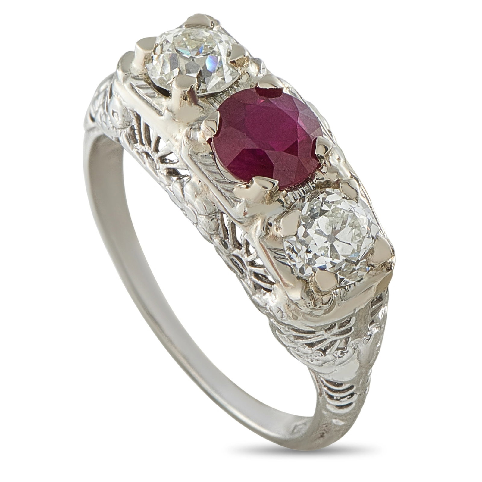 Ciner 18K White Gold 0.90ct Diamond and Ruby Art Deco Ring: An exquisite Art Deco three-stone ring in 18K white gold, centering a vivid oval ruby of approximately 0.75 carats flanked by two old European-cut diamonds in an elaborate openwork filigree mounting. 