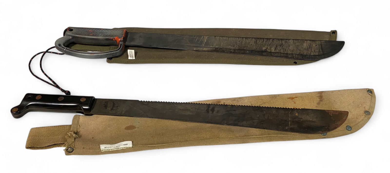 (2) US Ontario Military Machetes (One with Razorback) with Sheathes: See photos. 1- Ontario Knife, made in USA. Has seen use, but remains in good condition, with some nice color and character to it. Blade measures 17.5”, overall length 23.5”, 2- Ontario Kni