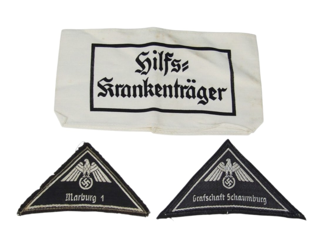 German WWII Stretcher Bearer Helper Armband & DRK (Red Cross) District Patches: Printed on soft cotton base. Scarce Bevo embroidered Red Cross District uniform shoulder patches. None glow under blacklight. See photos.