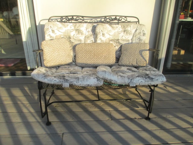 Black Metal Glider Bench: 45" long, includes grey/beige floral removable cushions and accent pillows, some paint flaking, Local Pickup Only 