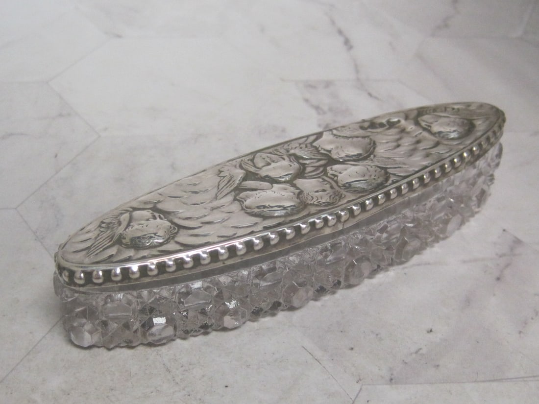 English Sterling Silver Dresser Box: Maidens & cherubs on cover, Marquise shape, London hallmarks, Daisy & button design glass base. 5 1/4" long