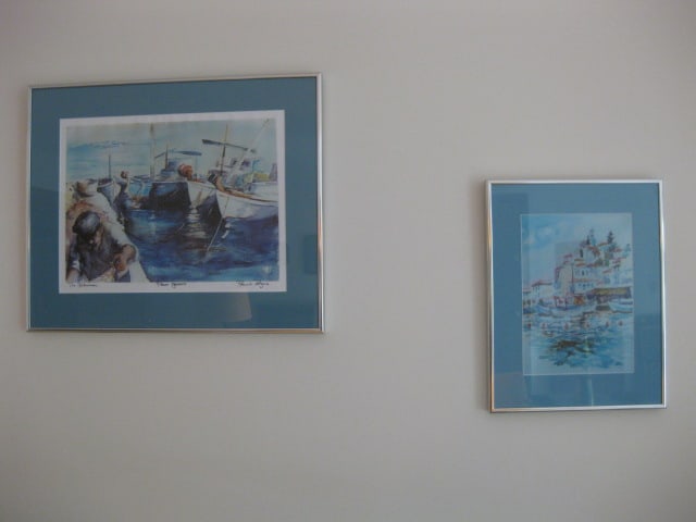 Two Framed and Matted Pamela Rogers Poros, Greece Prints of Watercolors: Marker Signed and Titled "The Fisherman" Poros, Greece 19 1/2" x 16 1/4", Fishing Village 11 1/4" x 14 1/4", has artist bio