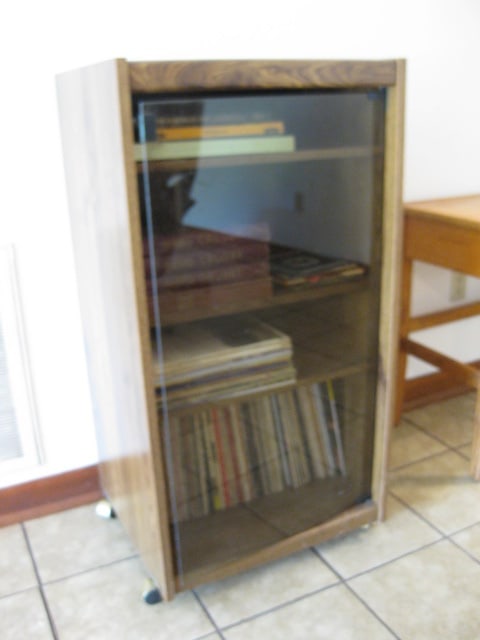 Record Cabinet with Various Speed Records: Cabinet 22" x 19 1/2" x 43"-cabinet has bronzed glass door and casters, Record speeds 45, 33 Sets and Vinyl LPs, Show Tunes, Easy Listening, Classical, Classic Country, etc. Johnny Cash, Bing Crosby, 