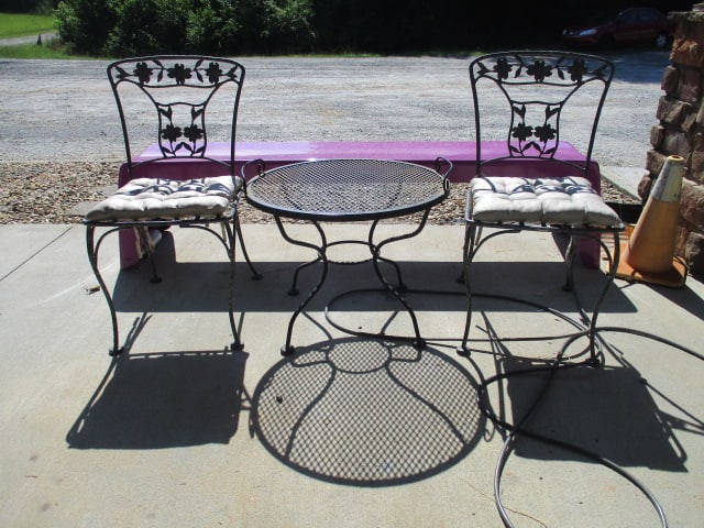 Pair of Black Wrought Iron Side Chairs and Black Metal Mesh Tray Table: (2)17"w chairs, table 25"dia x 19"h, tray top lifts off to serve, chairs have dogwood blossom designs, slight weathering and small rust spots, Local Pickup Only
