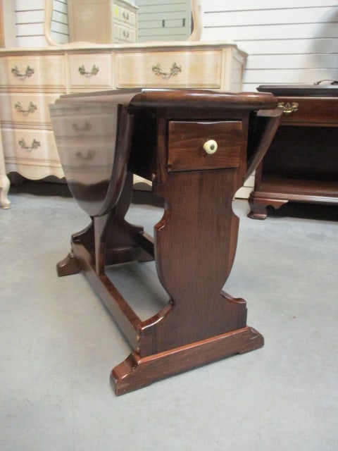 Ethan Allen Early American Style Dark Stained Pine Drop Leaf Lamp Table with Drawer: 13 1/2"(sides down)31 1/2"(sides up) x 28" x 23 1/2", dovetail drawer with porcelain pull, some scuffs and nick at leaf seam, Local Pickup Only