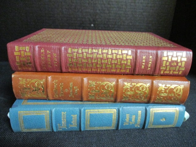 Three Eastman Press Leather Bound Classic Works of Literature: "The Adventures of Huckleberry Finn" by Mark Twain, "Gulliver's Travels" by Jonathan Swift and "Treasure Island" by Robert Louis Stevenson. Books copyrights range from 1960-80's