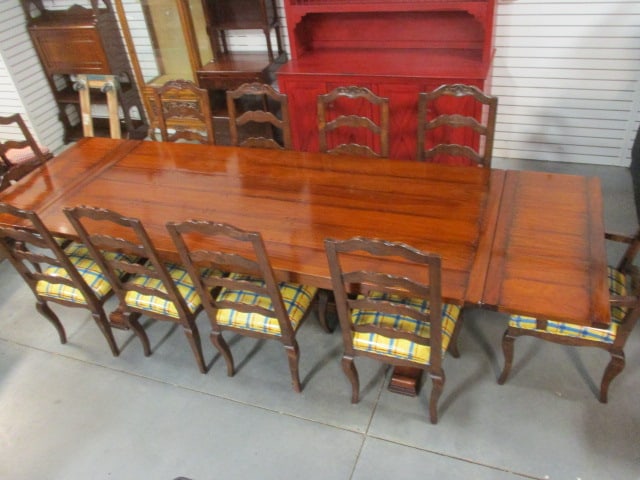 French Cottage Style Pegged Plank Draw Leaf Trestle Table and Ten Carved Ladder Back Chairs: Table 96"(leaves closed)132"(leaves extended) x 42" x 29 3/4", (2)22 1/2"Table has 18" leaf at each end, (2)22 1/2"w Arm chairs, (8)20 1/4"w Side chairs, Seats have vinyl coated brightly upholstered