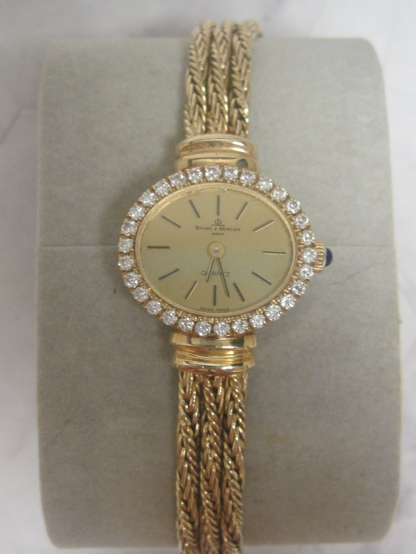 14k Gold Baume & Mercier Ladies Watch: Weighs 29.3 grams, With 14k Gold Multi-Strand rope band, diamond bezel, & blue cabochon stone set into winding crown, Needs battery