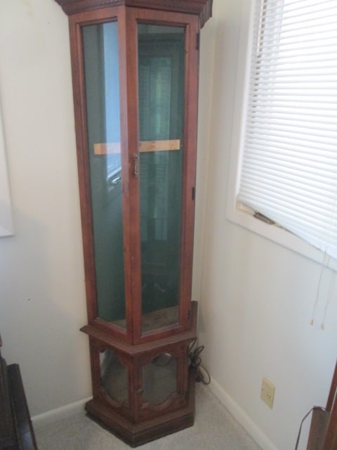 Traditional Wood Illuminated Curio/Gun Cabinet: One Piece Display Cabinet with Angled Sides and Crown Molding, 24 1/2" x 11" x 70 3/4", upper section has green felt back, custom peg/hook wood strip has been added, Lower section has mirror back,