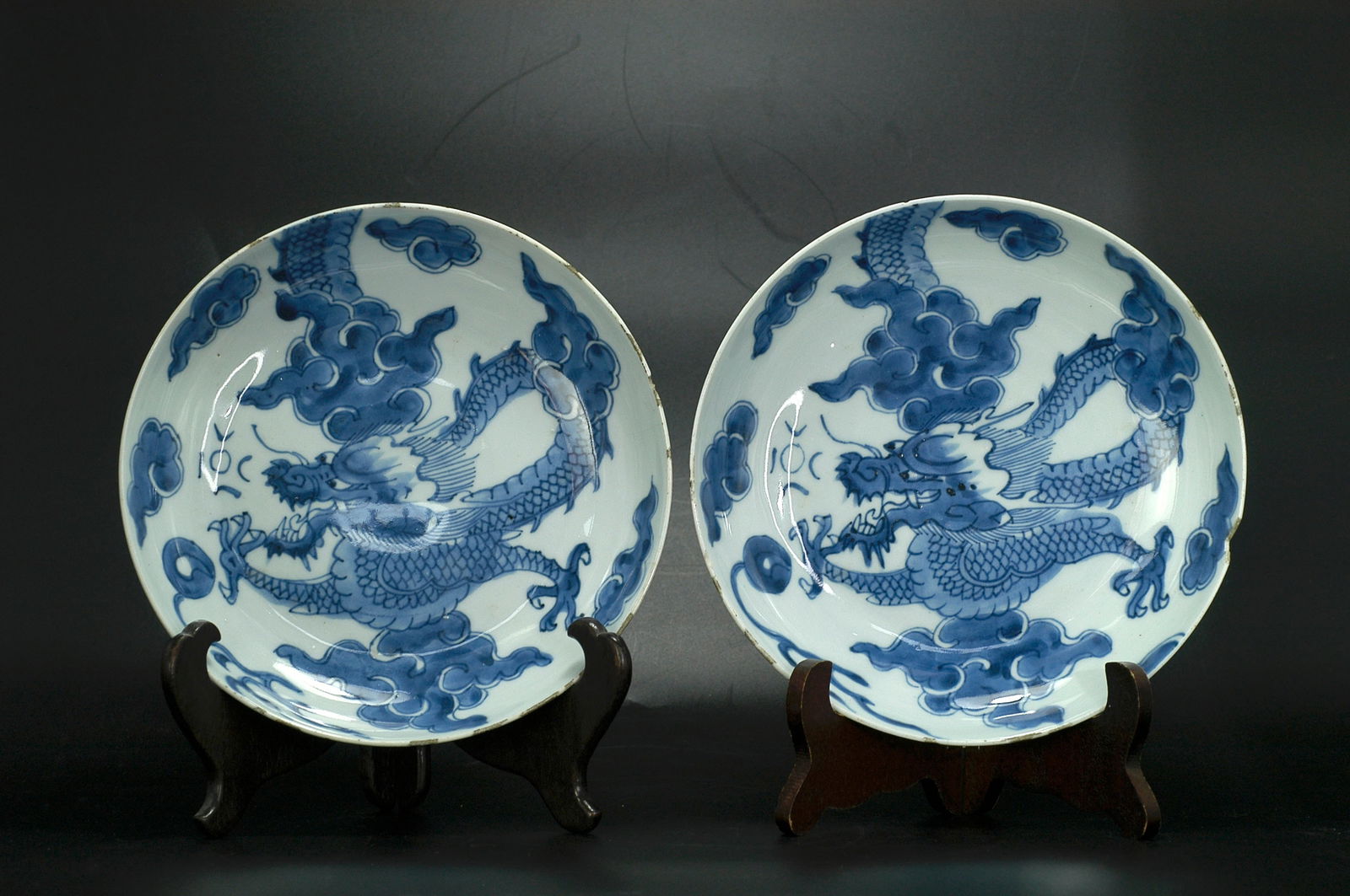 Qing Dynasty Blue and White Over-the-Wall Dragon Plate, a Pair: H3.9 cm x W20 cm. Qing Dynasty Kangxi Blue and White 'Climbing Dragon' Dishes (Pair, with apocryphal 'Da Ming Chenghua Nianzhi' marks). Dating: Authentic Kangxi period pieces, fine folk kiln blue and
