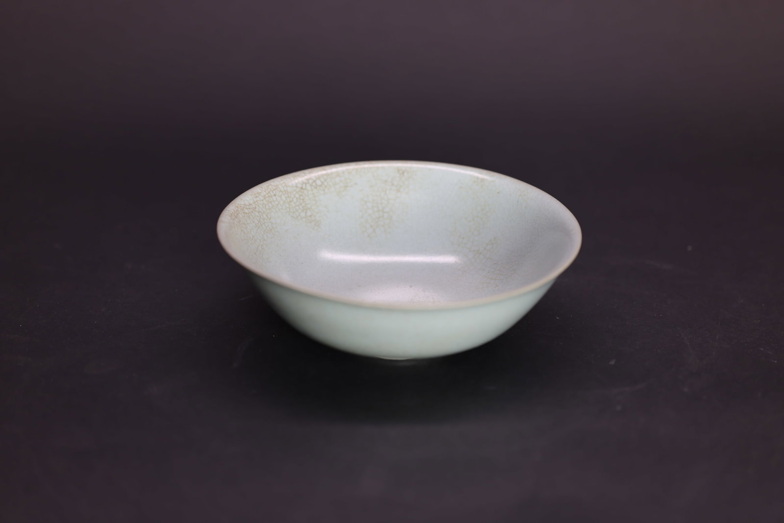 A Rare 'Ru' Sky-Blue Glazed Shallow Flared Bowl, Song Dynasty: Estimated Date: Northern Song Dynasty. Identified as an imperial Ru ware shallow bowl with sky-blue glaze.Attribution: The bowl is covered in a soft, opalescent sky-blue (tianqing) glaze with an intri