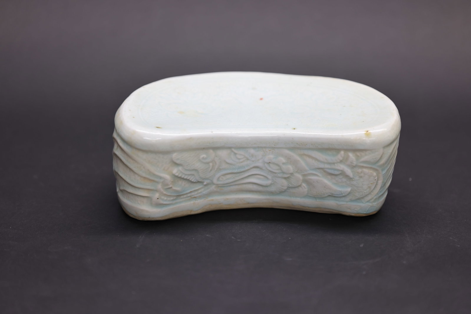 A 'Hutian' Shadow-Blue Glazed 'Qingbai' Ceramic Pillow with Incised 'Makara' Design, Song Dynasty: Estimated Date: Southern Song Dynasty. Attributed to the Hutian Kilns of Jingdezhen as a finely crafted qingbai ("Yingqing") porcelain pillow.Attribution: The pillow is covered in a luminous pale blue