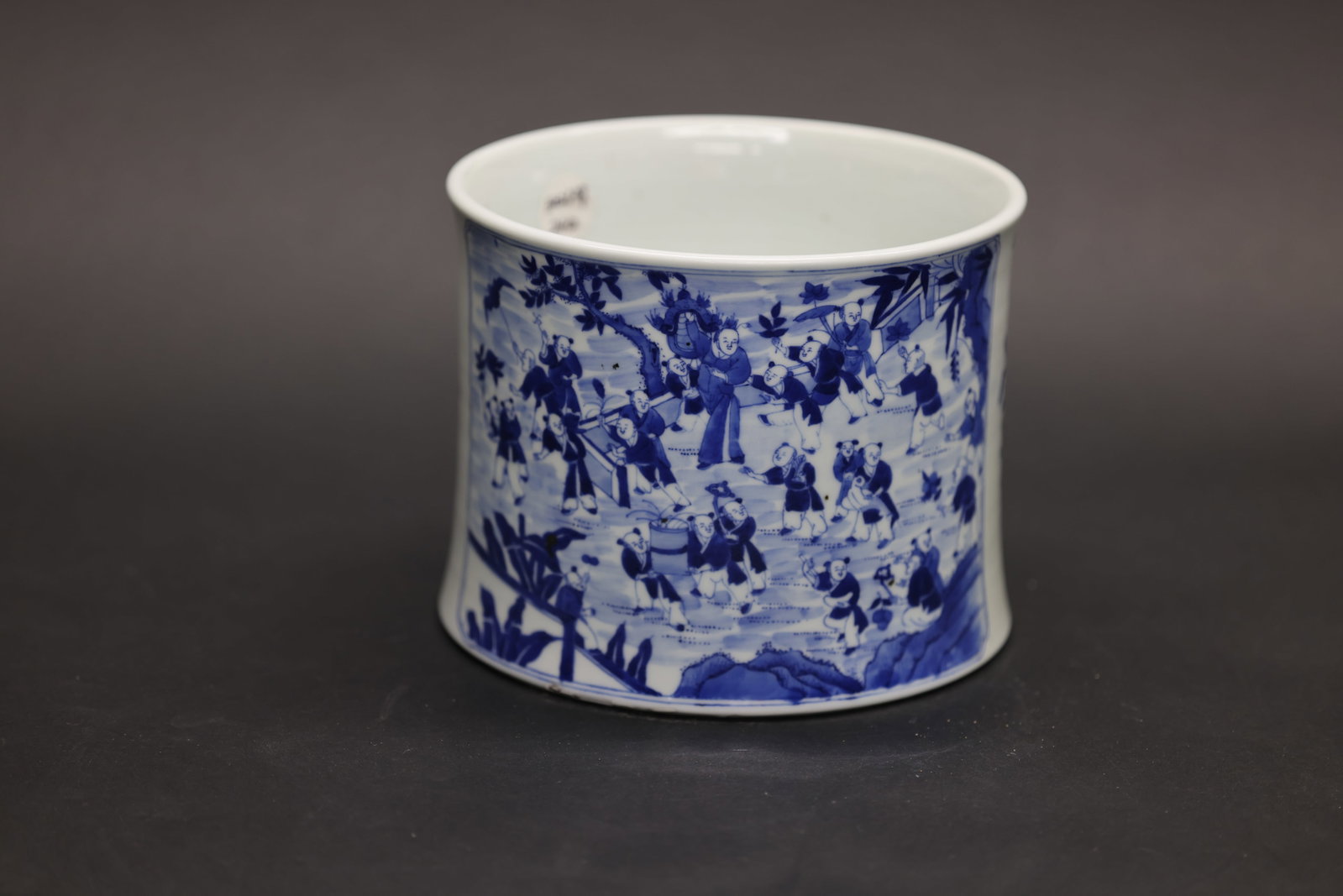 A Large Blue and White 'Hundred Boys' Waisted Brush Pot, Qing Dynasty: Estimated Date: Mid to Late Qing Dynasty. Attributed to the Jingdezhen kilns as a blue and white porcelain brush pot (bitong) for the scholar's desk.Attribution: The brush pot is of waisted cylindrica