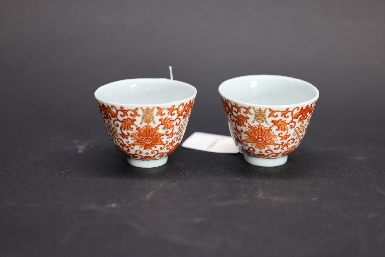 A Pair of Iron-Red and Gilt 'Lotus' Cups, Tongzhi Period: Estimated Date: Tongzhi Period, Qing Dynasty. A matched pair of imperial-style iron-red and gilt porcelain cups bearing the Tongzhi reign mark.Attribution: Each cup is finely potted and decorated in i