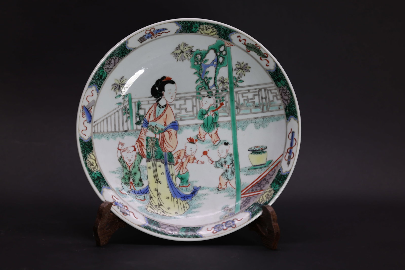 A 'Famille-Verte' 'Figures' Dish, Late Qing Dynasty, Kangxi Mark: Estimated Date: Late Qing to Republic Period. A Kangxi-style Wucai enamel porcelain charger bearing an apocryphal Kangxi reign mark.Attribution: The charger is of shallow, wide-rimmed form and decorat