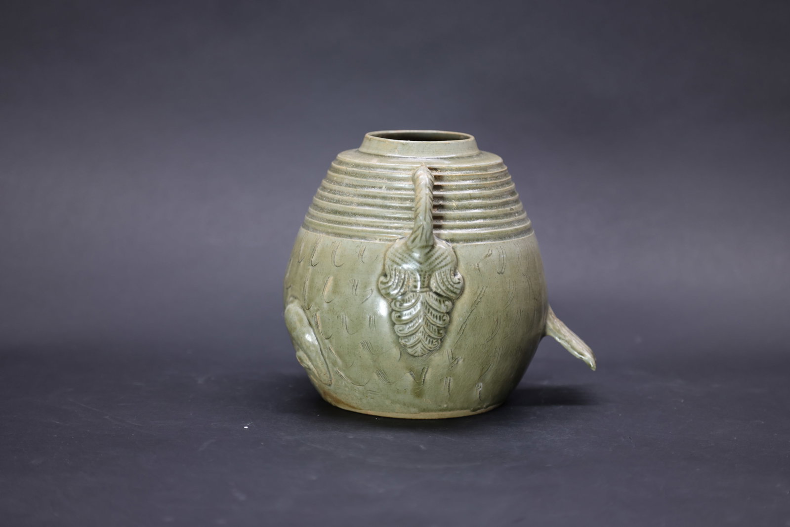A 'Yue' Celadon 'Fish-Shaped' Jar, Tang Dynasty: Estimated Date: Jin Dynasty. Attributed to the Yue kilns as a celadon fish-form covered storage jar.Attribution: The vessel is modeled in the form of a fish and covered overall with a soft grayish-gre