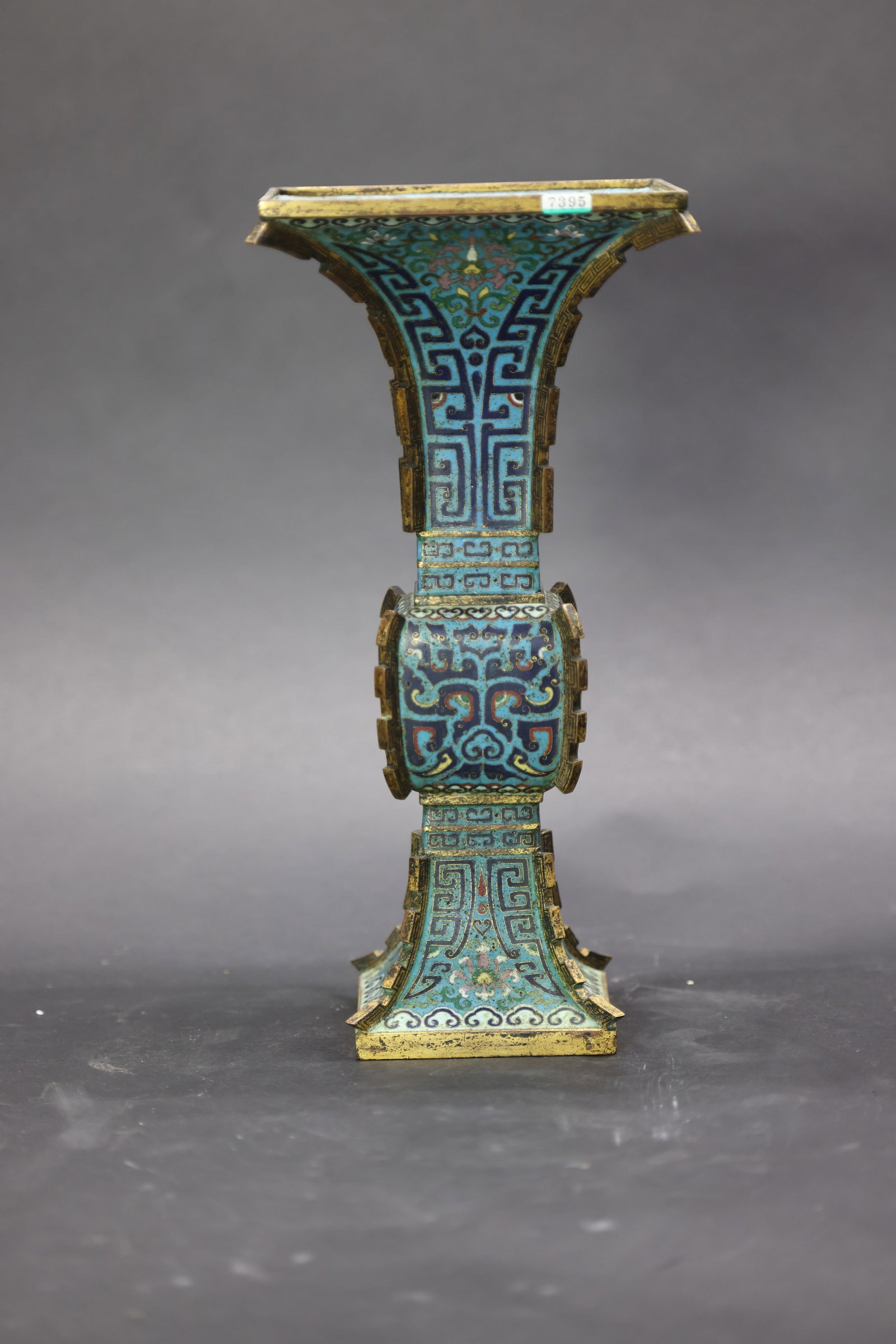 A Rare Cloisonné Enamel 'Archery' Square Gu-Vase, Qianlong Mark and Period: Estimated Date: Qianlong Style, Qing Dynasty. An imperial-style gilt-bronze cloisonné enamel fang gu vase bearing a Qianlong reign mark.Attribution: The vase is modeled after the ancient bronze squar