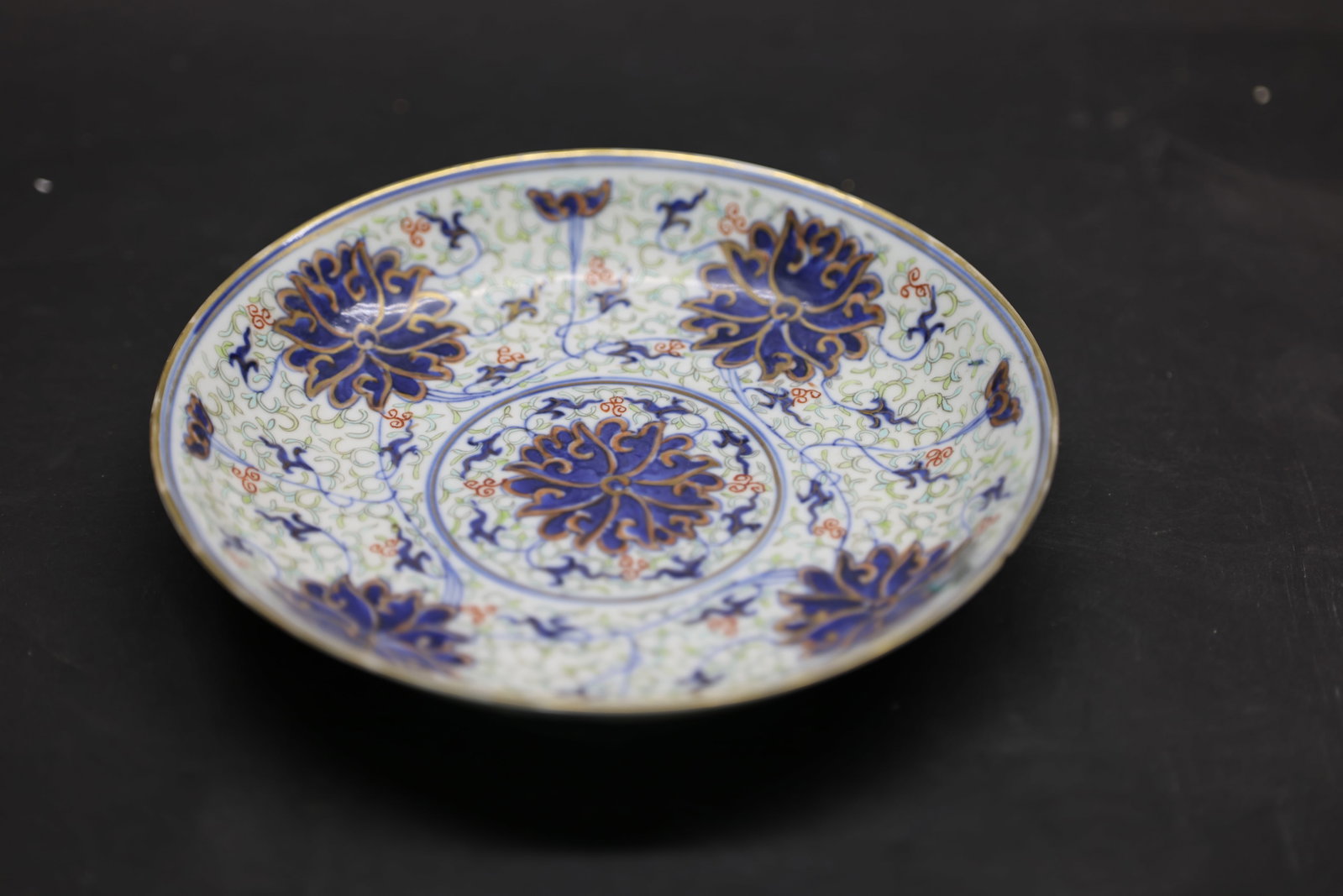 A Blue and White, Enamelled and Gilt 'Baoxianghua' Dish, Guangxu Mark and Period: Estimated Date: Guangxu Period, Qing Dynasty. An imperial-style blue and white, famille rose, and gilt porcelain charger bearing a Guangxu reign mark.Attribution: The dish is finely potted and covered
