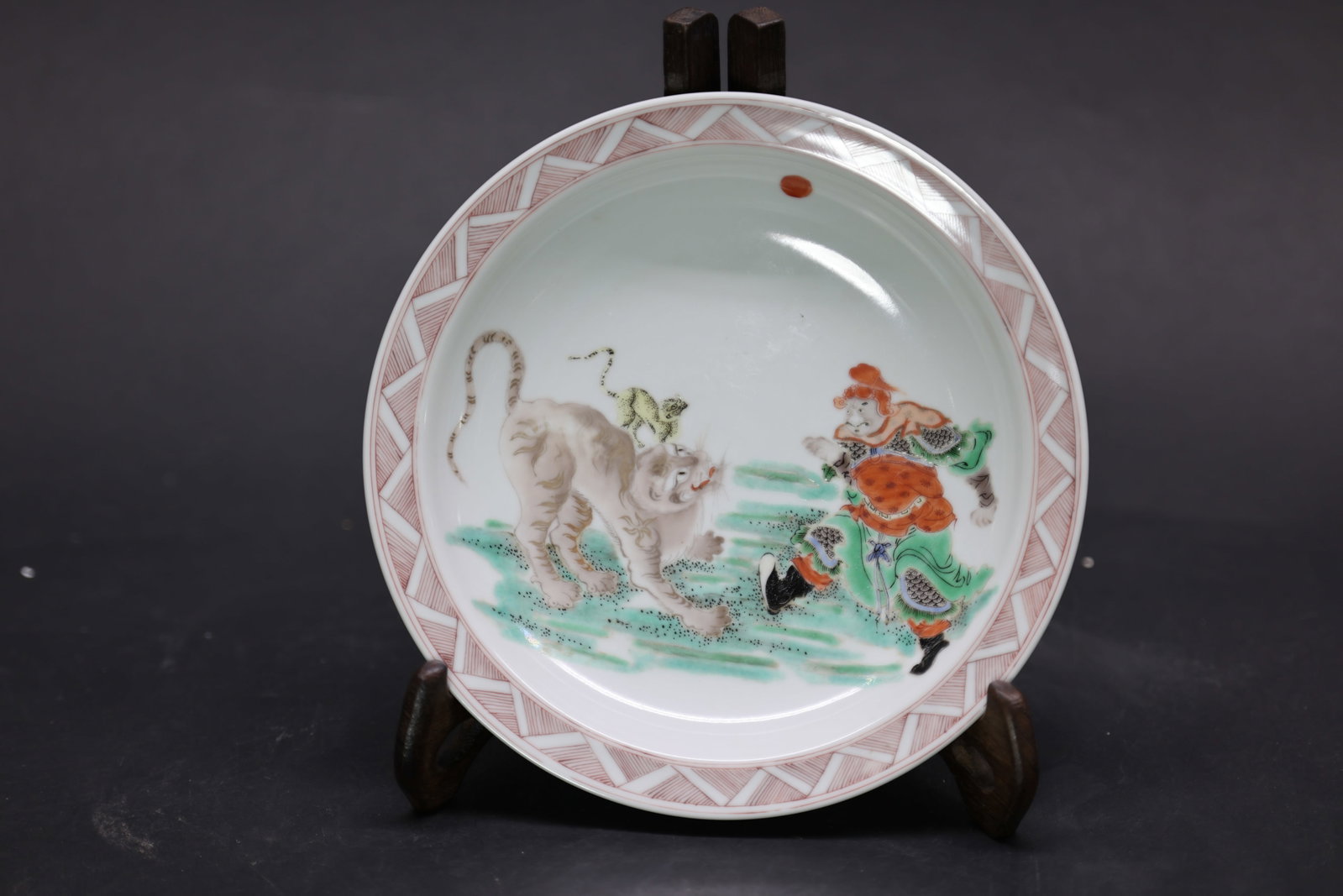 A 'Kangxi'-Style 'Wucai' 'Arhat and Tiger' Dish, Qing Dynasty: Estimated Date: Late Qing to Republic Period. A Kangxi-style famille verte porcelain narrative dish bearing an apocryphal "Made during the Kangxi Reign of the Great Qing" mark.Attribution: The dish is