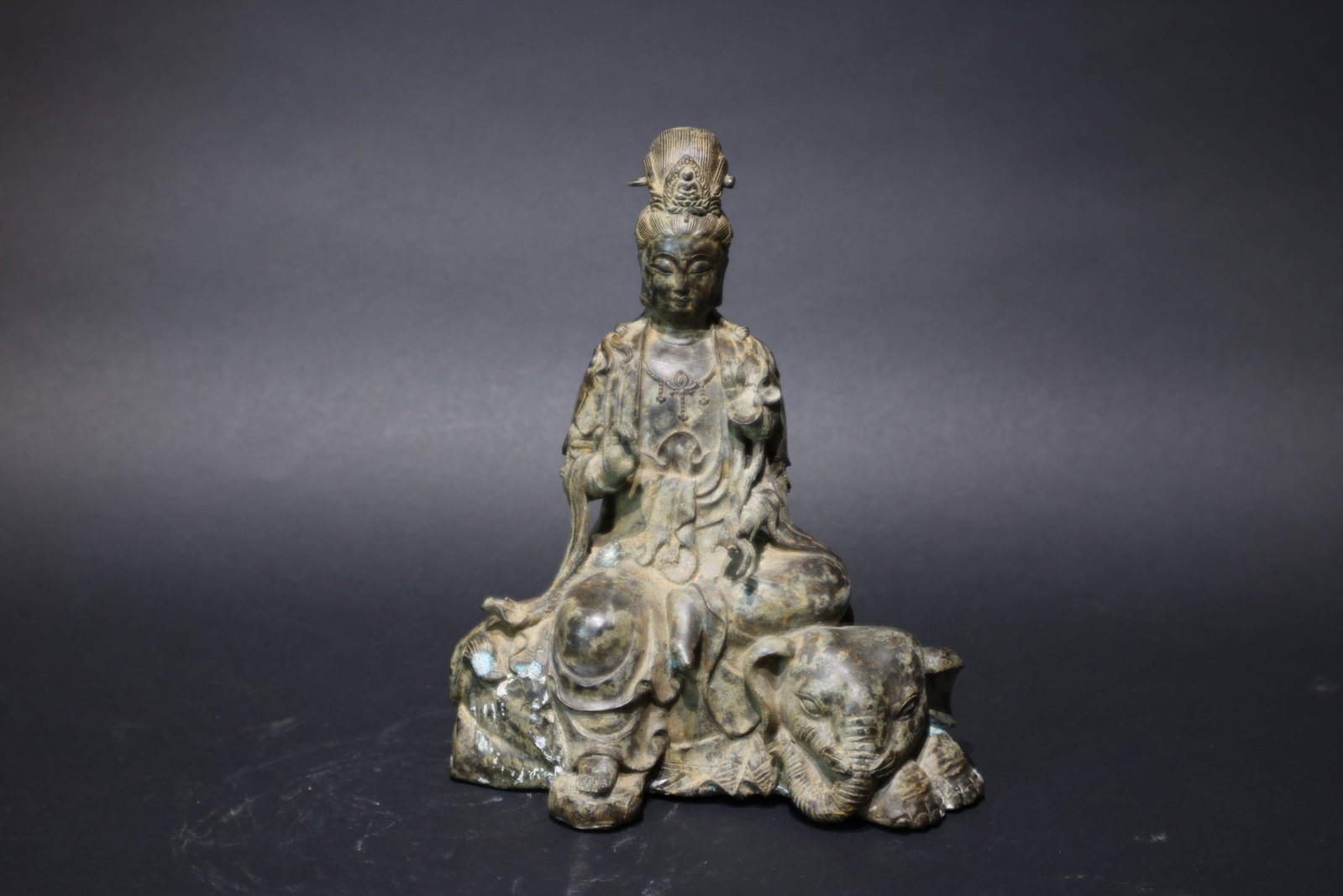 A 'Xuande' Mark Bronze Figure of Samantabhadra Recumbent on an Elephant: Estimated Date: Late Qing Dynasty to Republic Period. A cast brass figure of Samantabhadra (Puxian) on a six-tusked elephant with an apocryphal Xuande mark.Attribution: Cast in yellow brass, the sculp