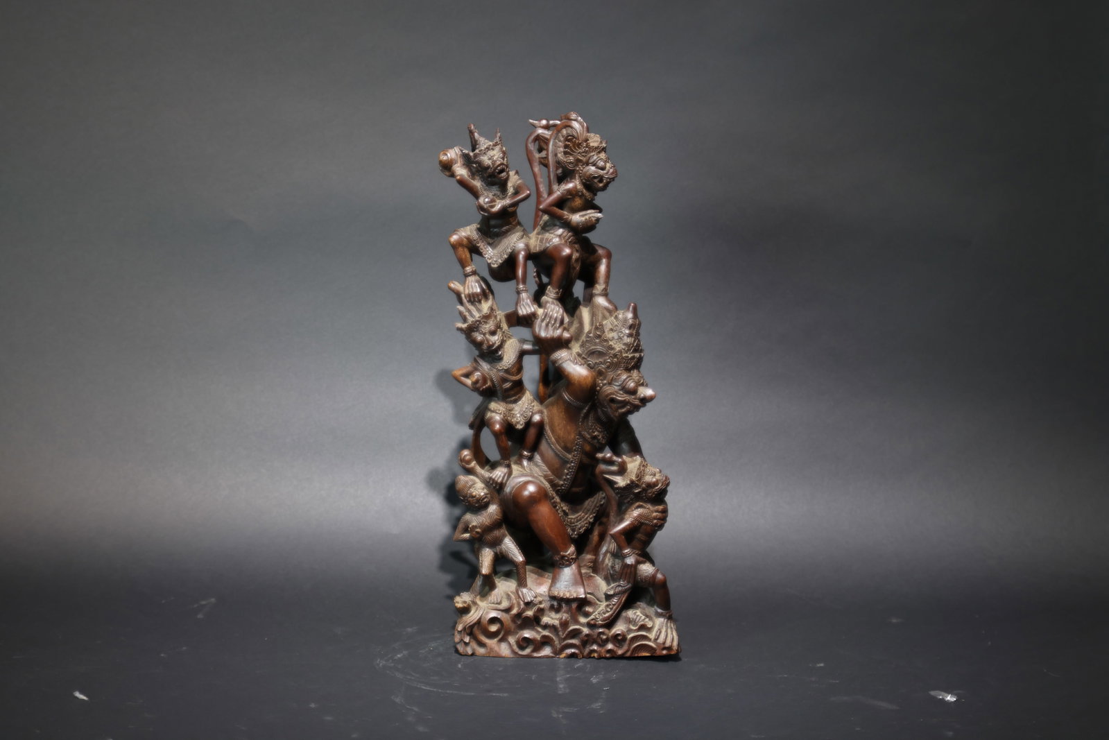 A Bali Hardwood Multi-Layered Openwork Carving of Hanuman and Deities, Southeast Asia: Estimated Date: Modern Period. A traditional Balinese carved hardwood figure of Hanuman and attendant deities.Attribution: Finely carved from a single block of dense tropical hardwood, the sculpture d