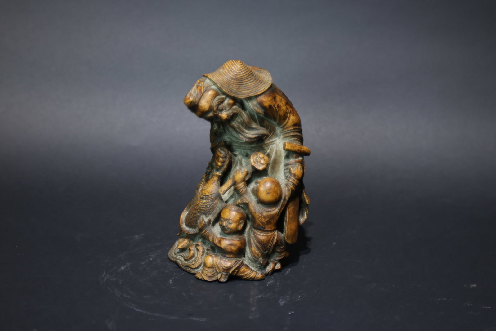 A Boxwood Carving of a Fisherman and Child, Qing Dynasty: Estimated Date: Late Qing Dynasty. A boxwood carving of a fisherman with attendants, conceived as a scholar's desk ornament.Attribution: Expertly carved from a single piece of boxwood (huangyangmu), t