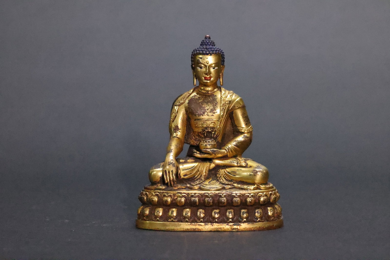 A Highly Important Gilt-Bronze Figure of Medicine Buddha, Bhaisajyaguru, Qing Dynasty: Estimated Date: Mid-Qing Dynasty. A gilt-bronze Medicine Buddha (Bhaisajyaguru) cast in the style of the Yongle period, with an apocryphal Ming inscription.Attribution: This finely cast gilt-bronze fi