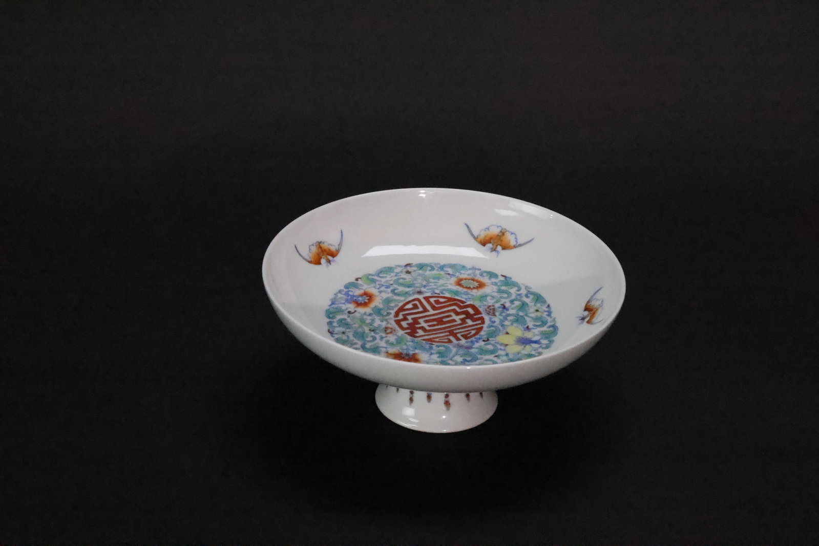 A 'Qing Qianlong' Mark Doucai 'Lotus and Five Bats' High-Footed Offering Dish: Estimated Date: Late Qing Dynasty. A doucai enamel high-footed offering dish in the style of the Qianlong imperial kilns, decorated with the auspicious Five Bats and Longevity motif.Attribution: This 