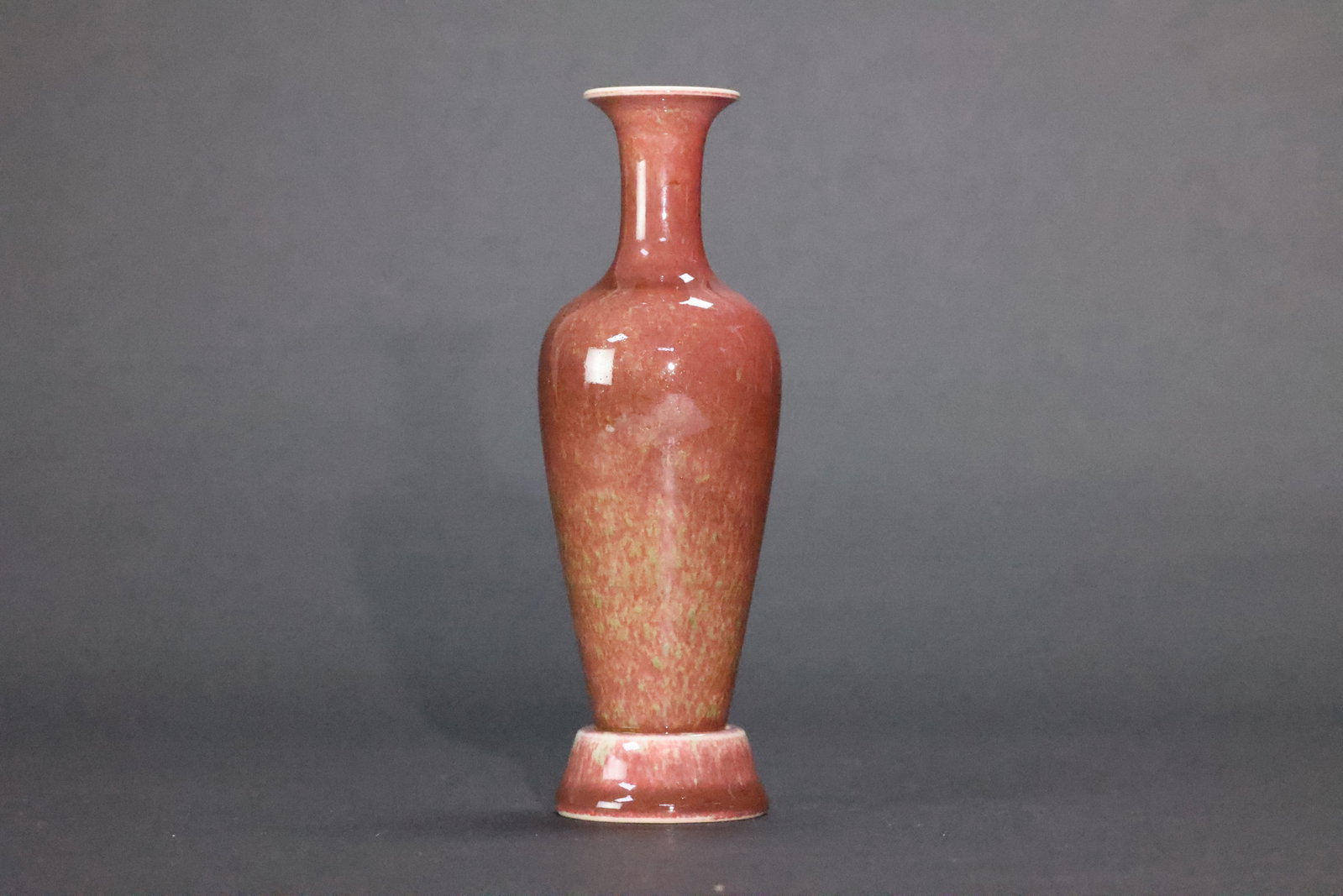 A 'Peachbloom'-Glazed 'Willow Leaf' Vase with Attached Stand, Late Qing Dynasty, In the Style of: Estimated Date: Late Qing Dynasty, Guangxu period (1875–1908). An archaistic peachbloom (jiangdouhong)-glazed willow-leaf vase bearing an apocryphal Kangxi reign mark.Attribution: This elegant willo