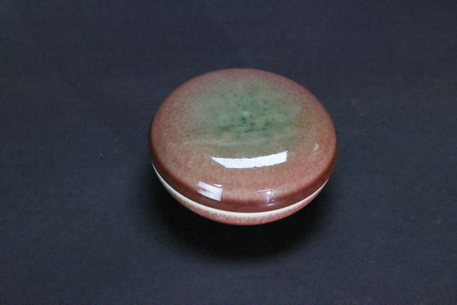 A 'Peachbloom'-Glazed Compressed Circular Paste Box and Cover, Late Qing Dynasty / Republic Period,: Estimated Date: Late Qing Dynasty to the Republican Period. A Jingdezhen peachbloom-style porcelain seal paste box (yinhe), bearing an apocryphal Kangxi reign mark.Attribution: This finely potted porc