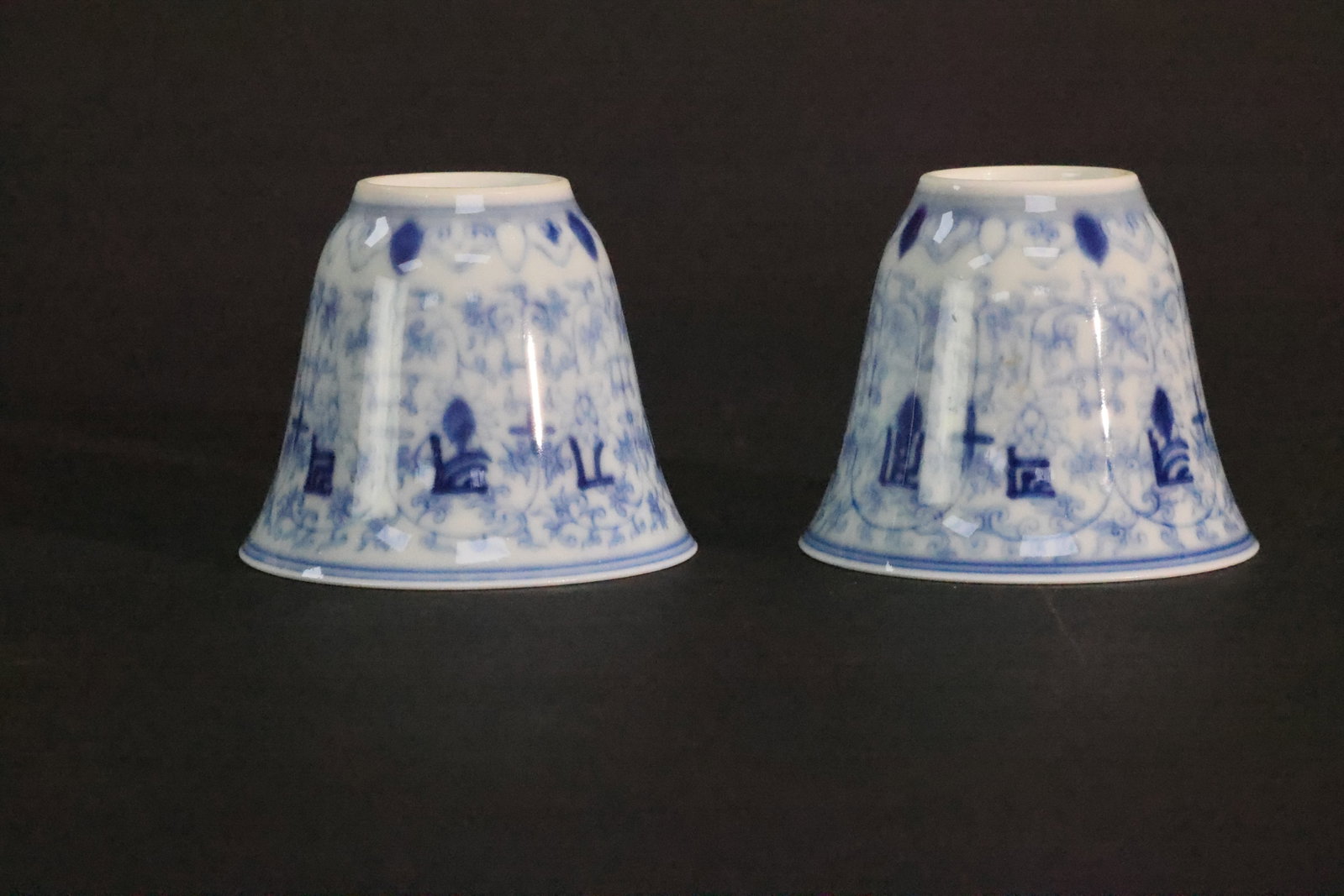 A Pair of 'Qing Yongzheng' Mark Blue and White 'Interlocking Lotus and Sanskrit' 'Bell-Shaped' Cups,: Estimated Date: Contemporary. A pair of blue-and-white porcelain cups in the style of the Yongzheng period, bearing apocryphal "Da Qing Yongzheng Nianzhi" reign marks.Attribution: This pair of porcela