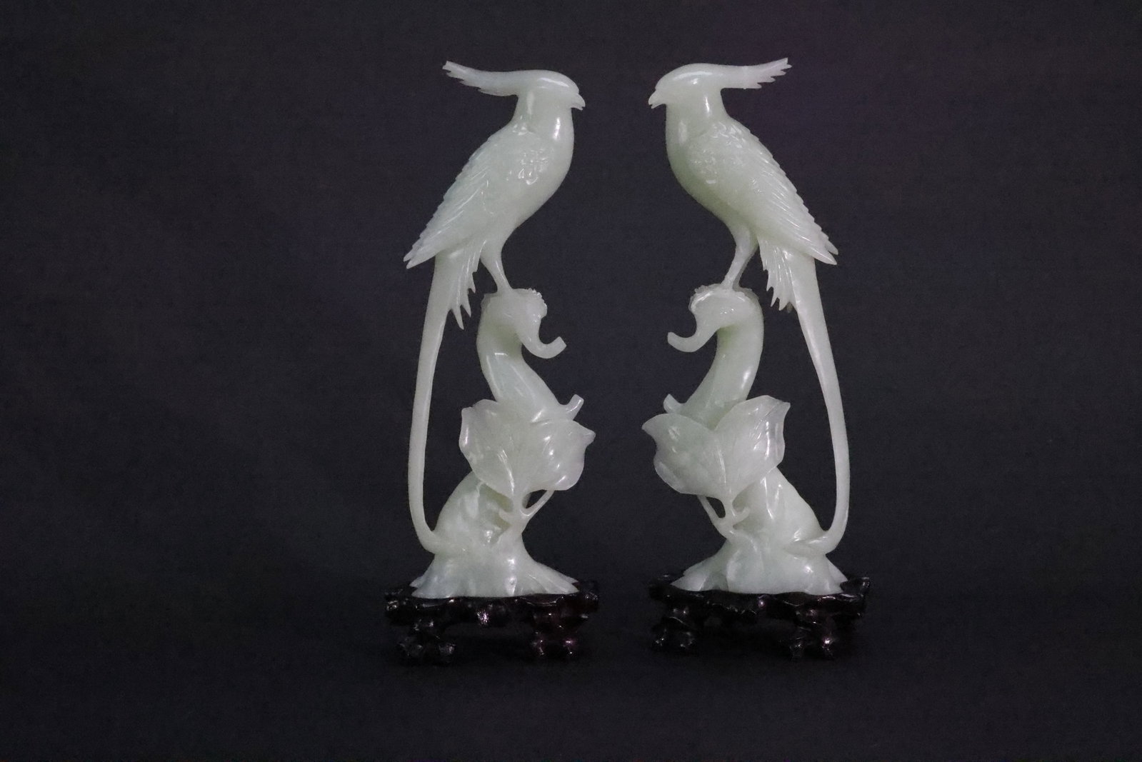 A Pair of Xiuyan Jade 'Ribbon Birds and Melons' Carvings, Modern Period: Estimated Date: Modern (post-1949 to contemporary). A pair of carved Xiuyu (Serpentine) ornamental sculptures with hardwood stands.Attribution: This pair of decorative carvings is executed in Xiuyu (s
