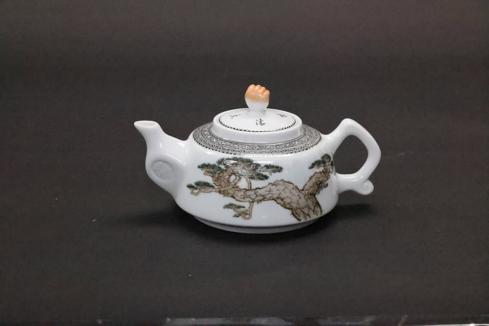 A Famille Rose 'Pine and Poetic Inscription' Teapot and Cover, Modern Period, 'Wang Xiliang' Mark: Estimated Date: Contemporary. A Jingdezhen famille rose teapot in the style of a master-decorated scholarly tea vessel.Attribution: This porcelain teapot is a contemporary Jingdezhen production create